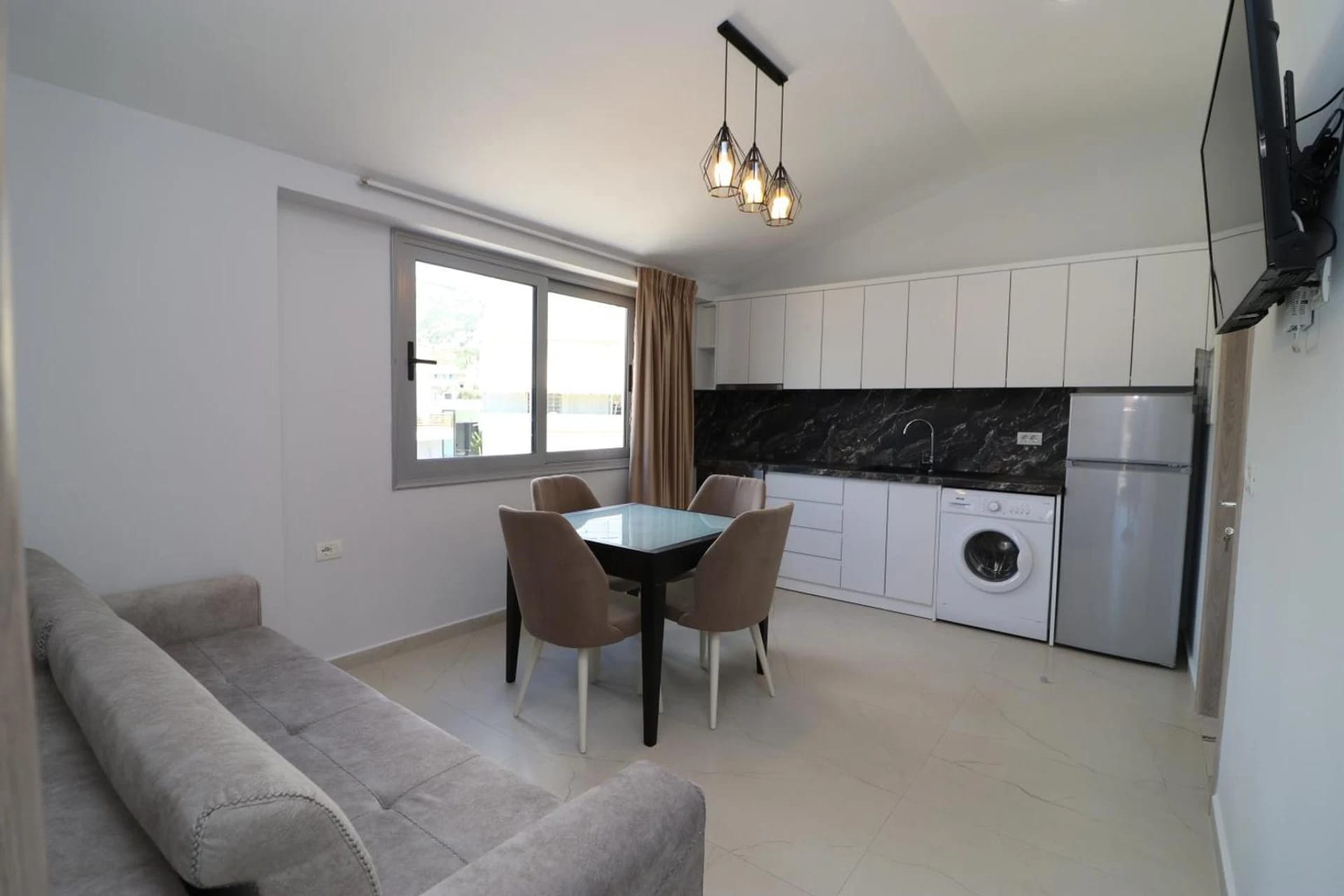 Apartment kitchen and living area with a sofa, dining table and balcony door