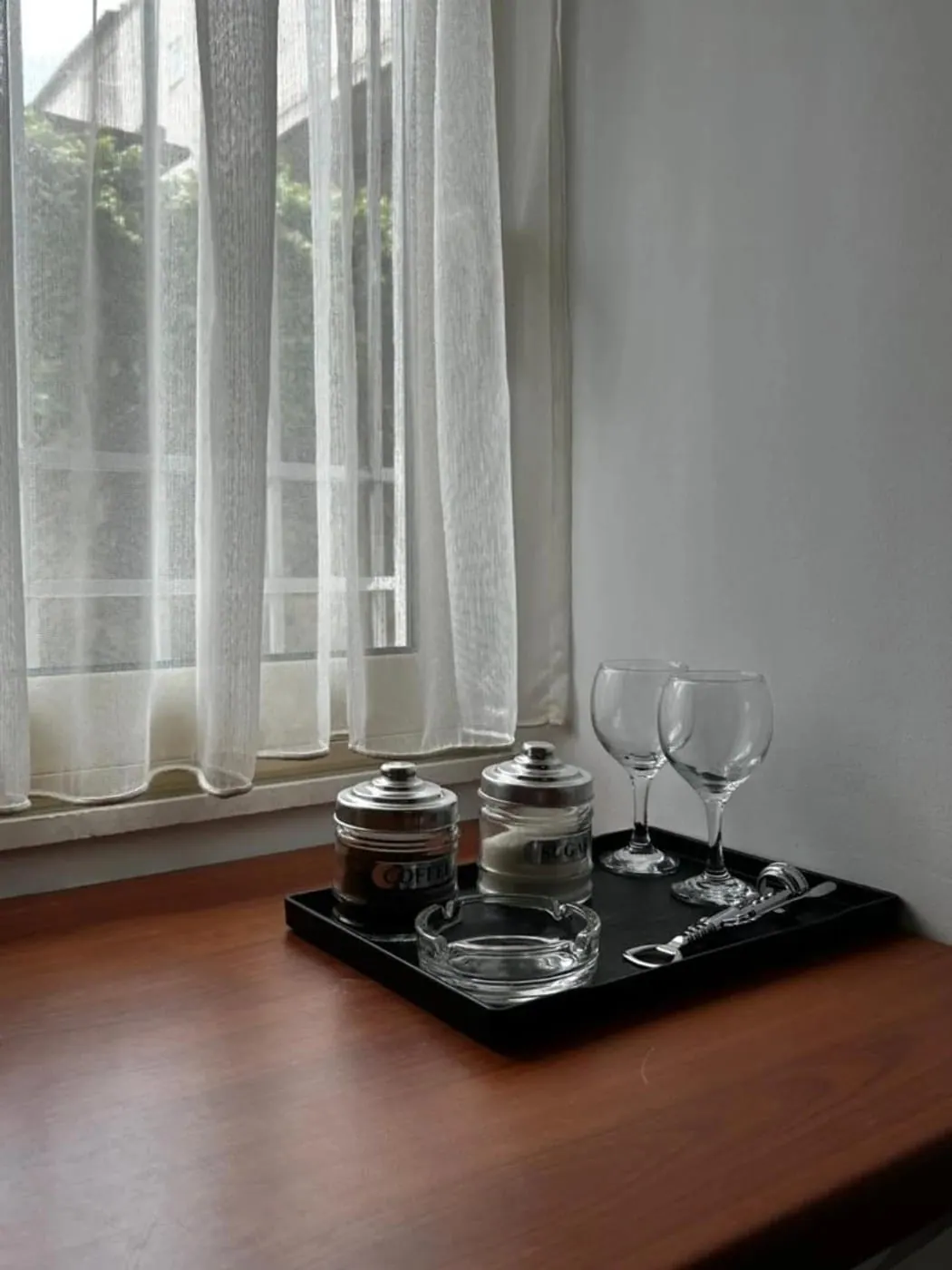 Rolled towels in a woven basket beside a linen curtain and a walnut floor